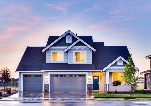 Beautiful two-story house with illuminated windows and garage at dusk.